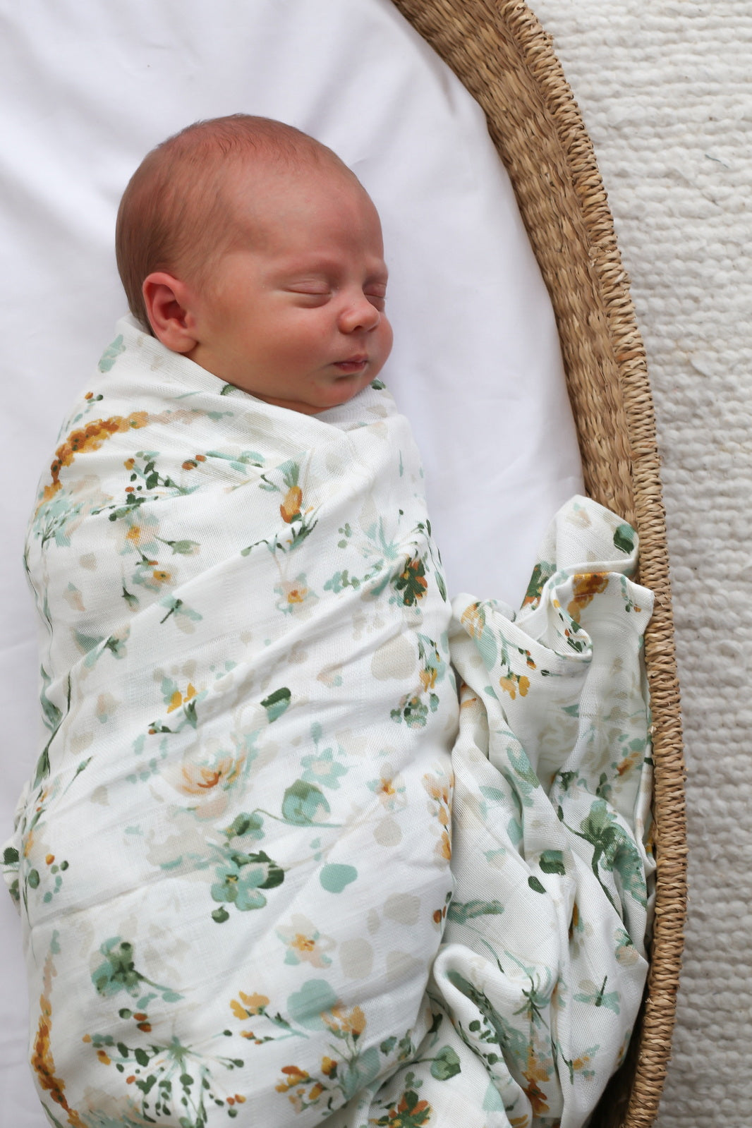 Baby laying in Moses Basket, wrapped in Spring Melody Muslin Wrap, designed by Burrow and Be