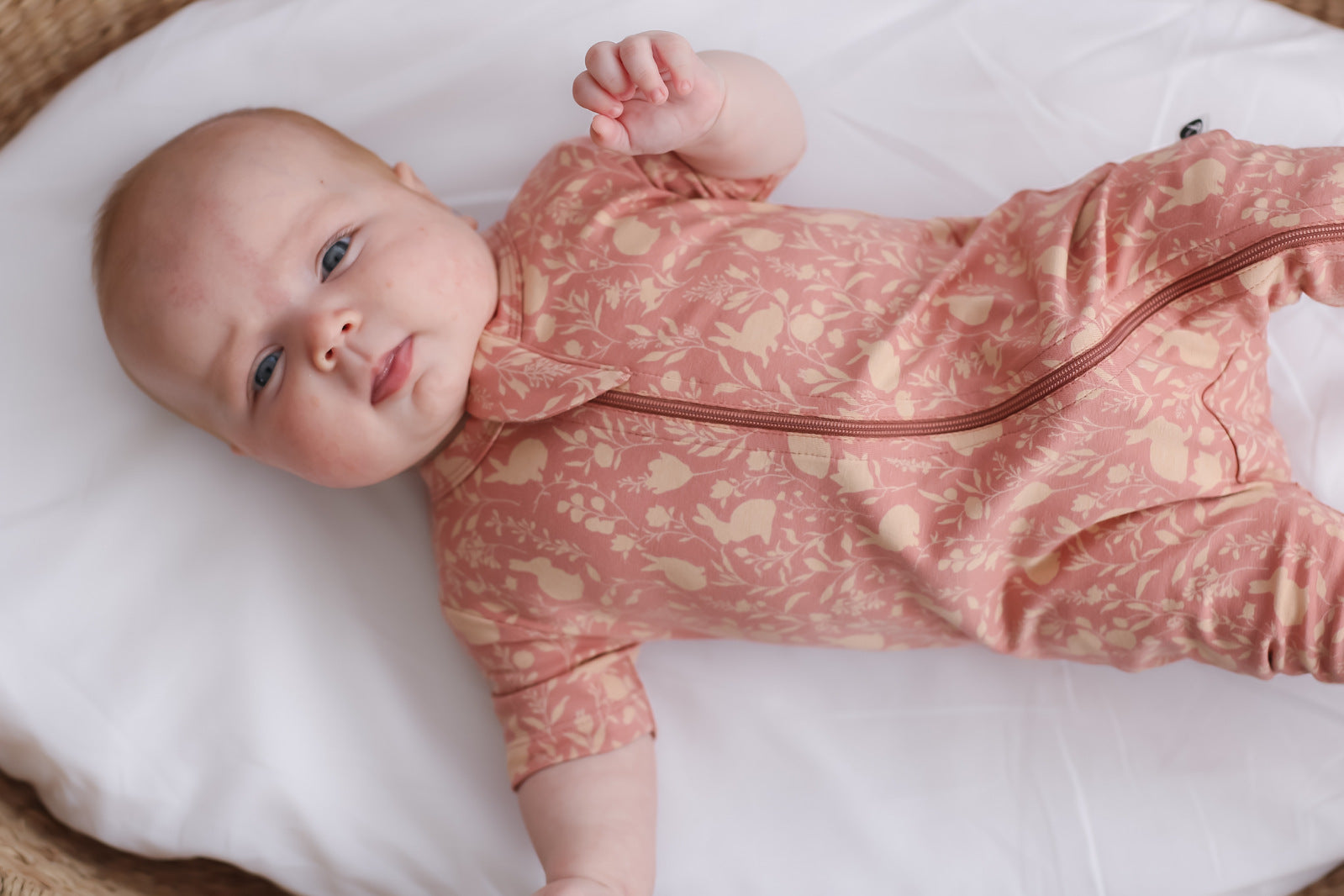 Baby in moses basket wearing Burrow and Be Mead-Doe Zip Suit