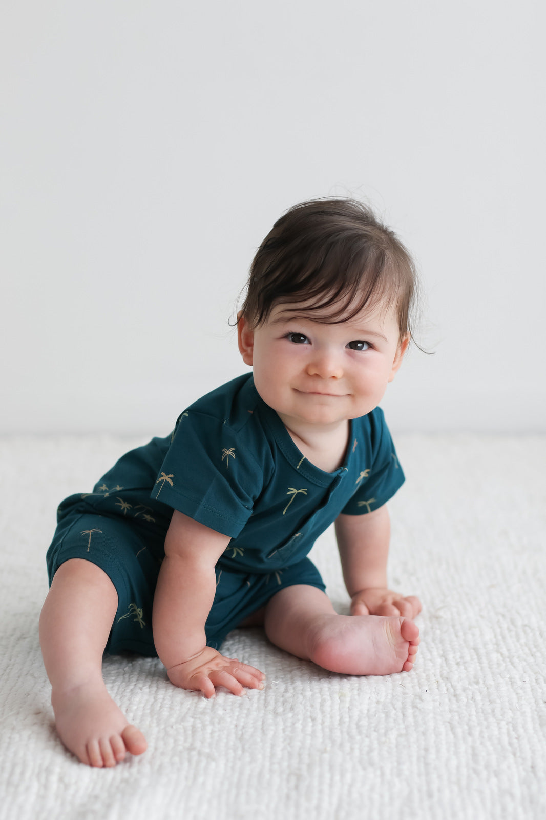 Baby sitting on the floor while wearing Palm Alex Romper from Burrow and Be