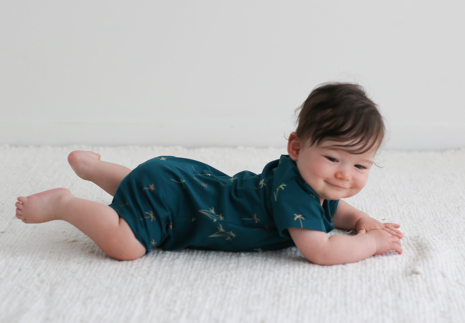 Baby lying on the floor with feet up while wearing Palm Alex Romper from Burrow and Be