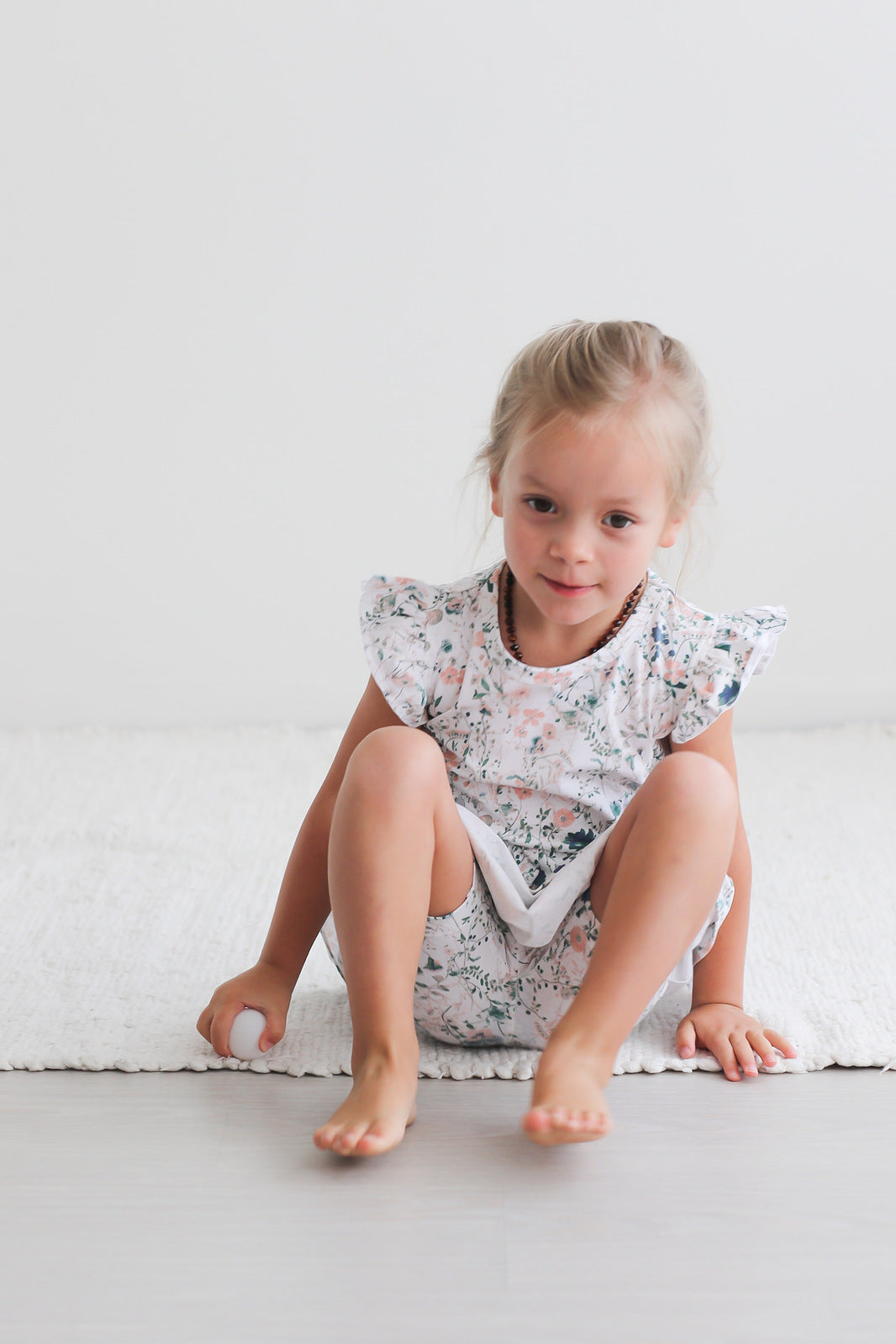 Girl standing in front of white background, wearing Wildflower Flutter Dress and Wildflower Bike Shorts, both designed by Burrow and Be