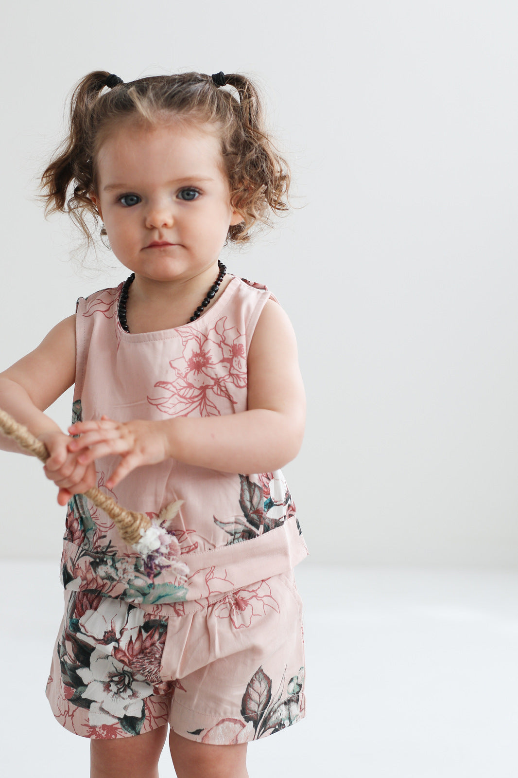 Baby girl standing in front of white background wearing Tropical Bouquet Lyla Shorts - Fleur and Tropical Bouquet Lyla Singlet, both designed by Burrow and Be
