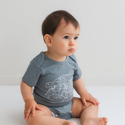Baby boy sitting on a white floor against a white background wearing Lost on Storm Bodysuit, designed by Burrow and Be